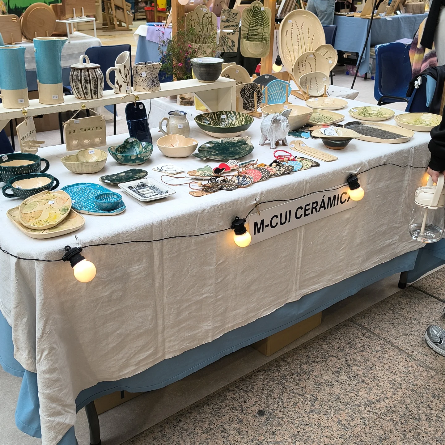 Puesto de MCui Cerámica en feria, vista completa con jarras, platos y piezas decorativas