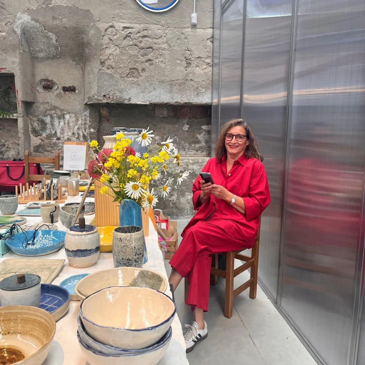 Marta en su taller, descansando entre piezas y un ramo de flores silvestres